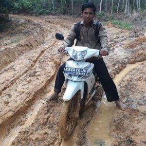 Warga ketika melalui akses jalan menuju ke Desa Pelinggang yang dipenuhi kubangan lumpur