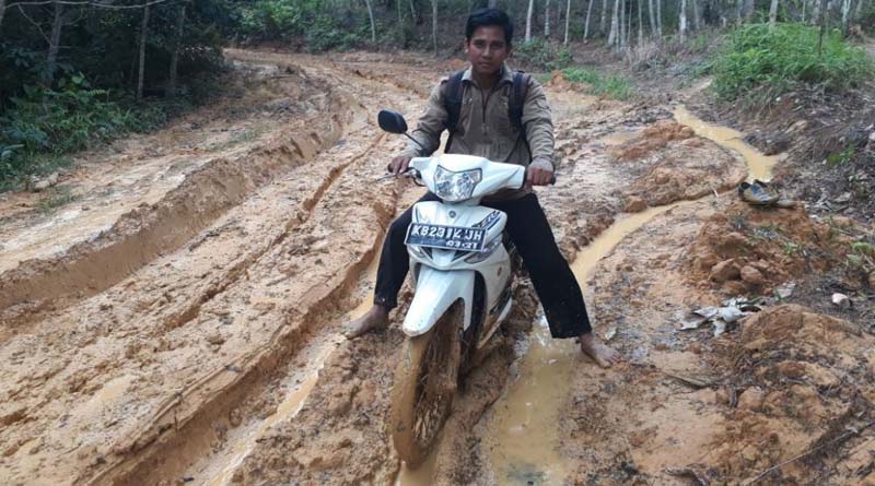 Warga ketika melalui akses jalan menuju ke Desa Pelinggang yang dipenuhi kubangan lumpur