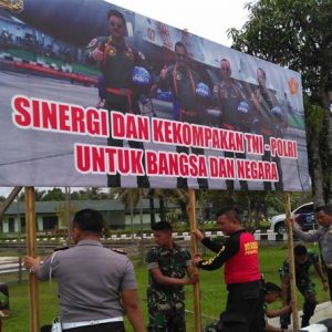 Anggota TNI dan Polri ketika memasang spanduk bersama-sama di depan markas Kompi Senapan A Nanga Pinoh