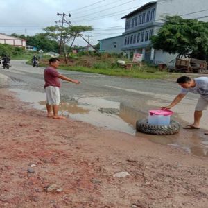 Warga ketika menutupi titik jalan yang berlubang dan digenangi air, agar tidak ada pengendara yang menjadi korban ---Dedi Irawan